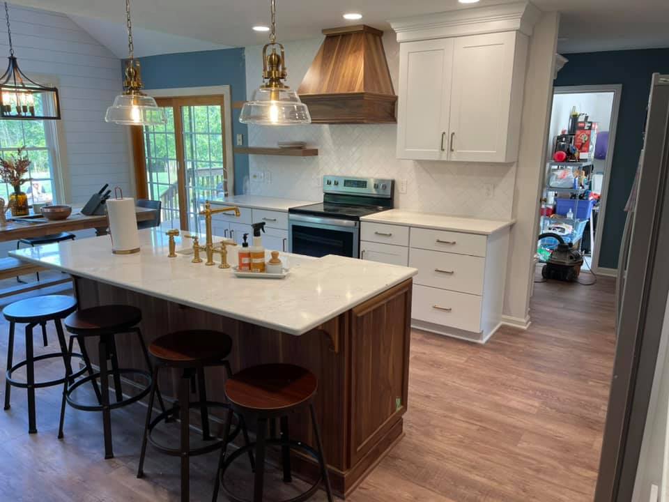 Welcoming kitchen centers on a large island. White cabinets mix with steel and wood. 