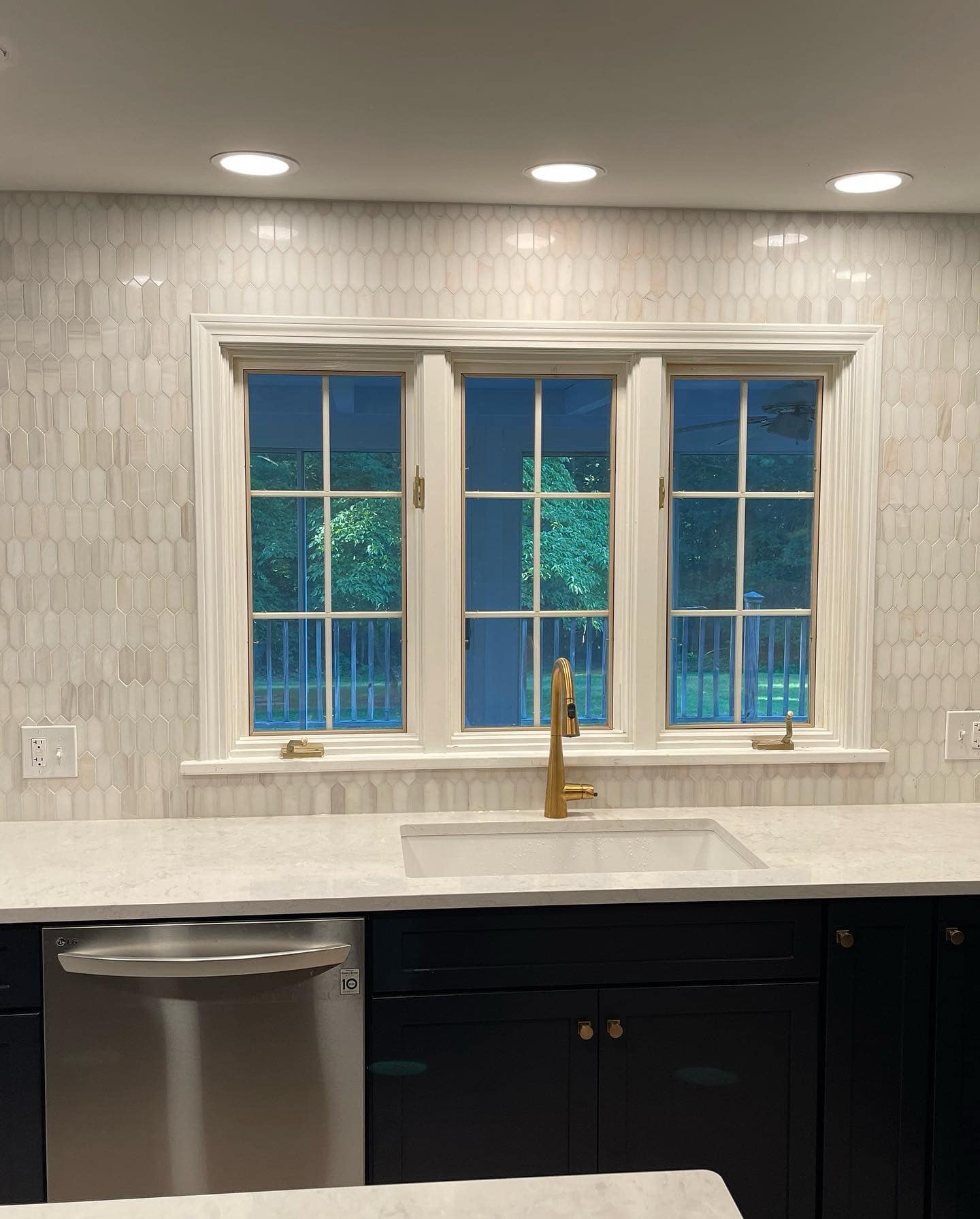 Elegant kitchen design with white counter, gold faucet and geometric marble backsplash!